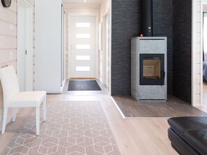 A modern interior with a fireplace, a white chair, and a patterned rug. - Saana 3 by Interhome (Enontekiö)