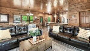 Un intérieur en bois avec des canapés en cuir, un coin repas et une cuisine.