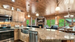 Une cuisine moderne dotée de plans de travail en granit, d’appareils électroménagers en acier inoxydable, d’armoires en bois et d’un grand îlot central.