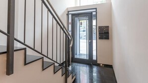 Un escalier moderne avec des rampes noires et une porte en verre donnant sur un espace extérieur.
