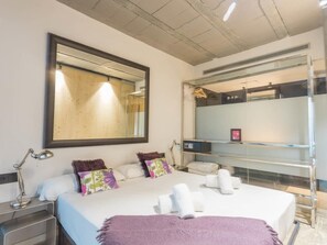 A modern hotel room with a large bed, a mirror, a desk with a lamp, and a glass shower enclosure. - My Space Barcelona Apart. with shared terrace in Sant Gervasi per months (Barcelona)