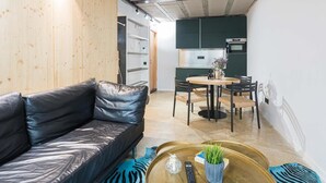 Ett modernt vardagsrum med en lädersoffa, ett soffbord med en växt och en matplats med ett runt bord och stolar.
