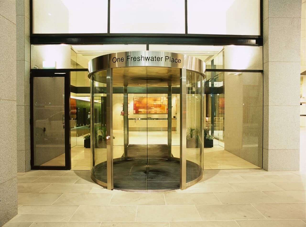Une porte tournante marque l’entrée d’un immeuble portant l’inscription « One Freshwater Place ».