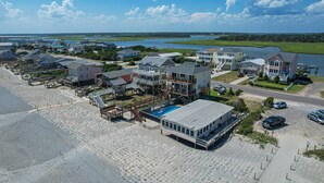 Un quartier résidentiel situé sur la côte, avec des propriétés donnant sur la plage, notamment des maisons dotées de terrasses et d’une piscine.