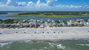Vue aérienne d’une zone résidentielle côtière, avec des maisons, une plage et un port de plaisance.