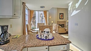 Una cocina equipada con cafetera, microondas y tostadora. Hay un comedor con una silla y una mesa.