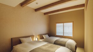 Un dormitorio con dos camas, vigas de madera en el techo, una ventana y una mesita de noche con lámpara.