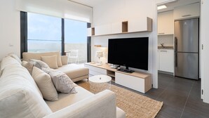 Ett modernt vardagsrum med soffa, TV och köksdel.