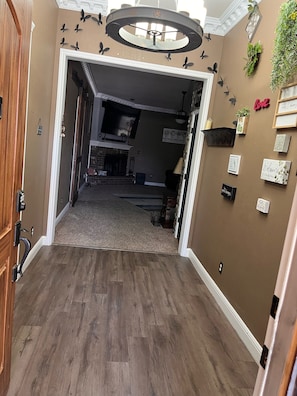 Un couloir doté d’un plancher en bois, d’une cheminée et d’un mur décoré de divers panneaux et plantes.
