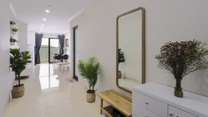 A modern hotel room with a large mirror, a wooden bench, and potted plants.