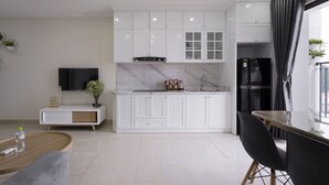 A modern kitchen with white cabinets, a built-in oven, and a black refrigerator.