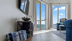 Een moderne woonkamer met een grote schuifglazen deur die uitkomt op een balkon met uitzicht op zee.