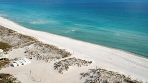 Een strand met helder turquoise water, een zandstrand en een gebouw met een witte gevel.