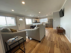 Una sala de estar moderna con un sofá, una mesa de centro y un televisor montado en la pared.