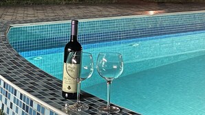 A swimming pool with a tiled edge, a bottle of Merlot wine, and two wine glasses on the poolside. - 3 Bedroom Apartment with pool (Celuga)