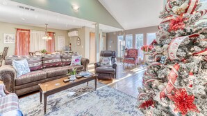 Un salón amplio con un gran ventanal, chimenea y un árbol de Navidad.