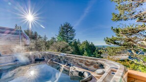 Jacuzzi con terraza de madera, rodeado de árboles y un cielo despejado.
