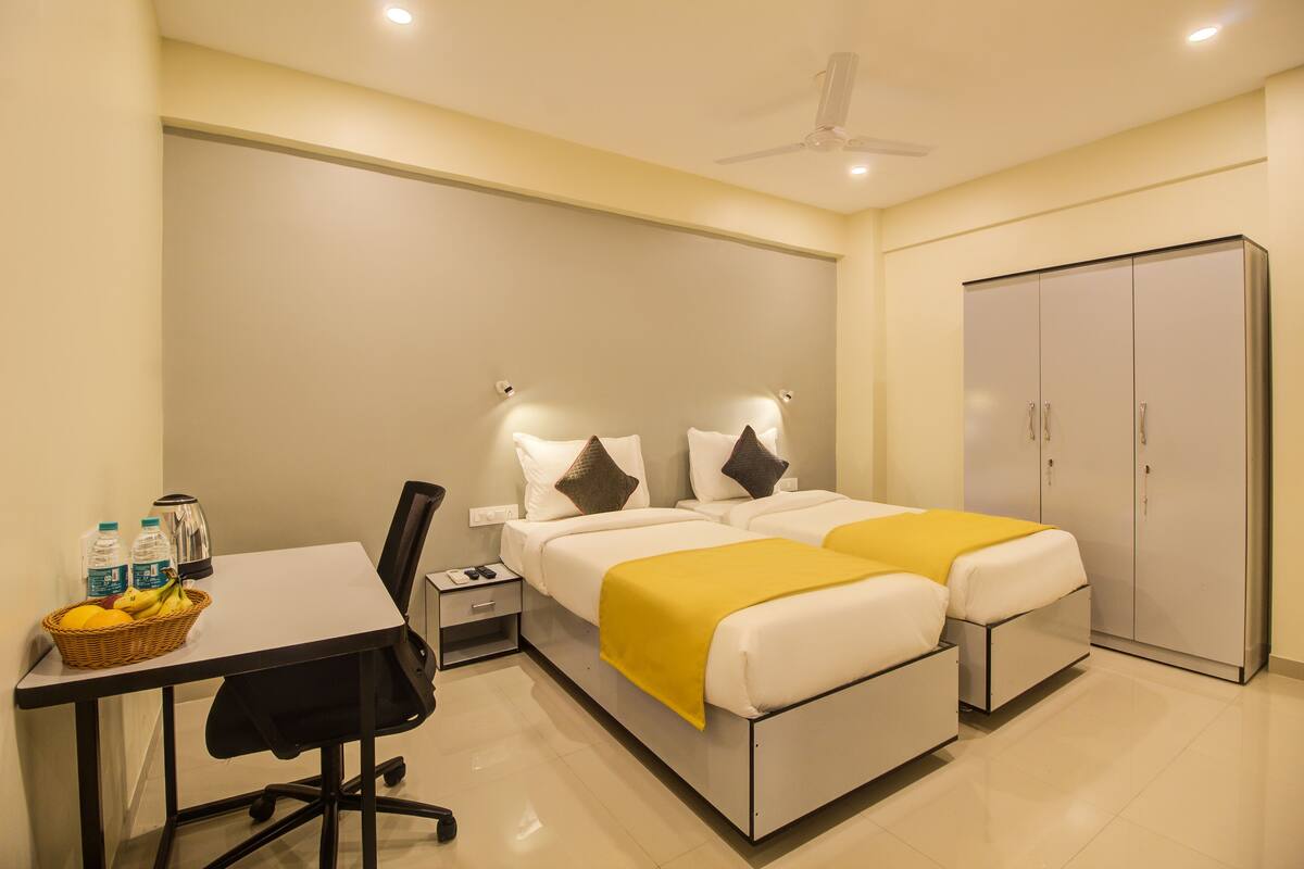 A hotel room with a bed, bedside tables, a desk with a chair, a wardrobe, and a ceiling fan.