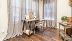 Une pièce avec une table en bois, une chaise et une petite étagère sur laquelle se trouve une plante.
