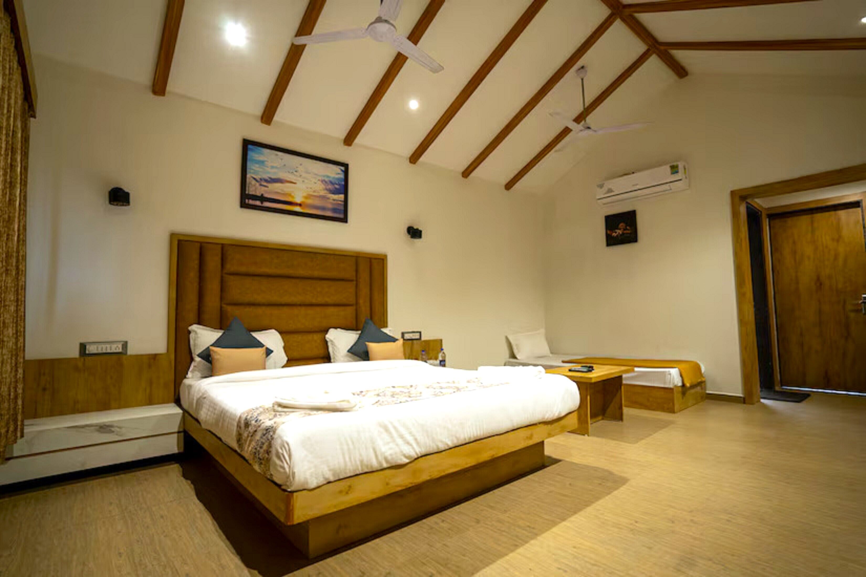Un dormitorio con cama de madera, una mesita de noche, una silla, un ventilador de techo y un cuadro en la pared.