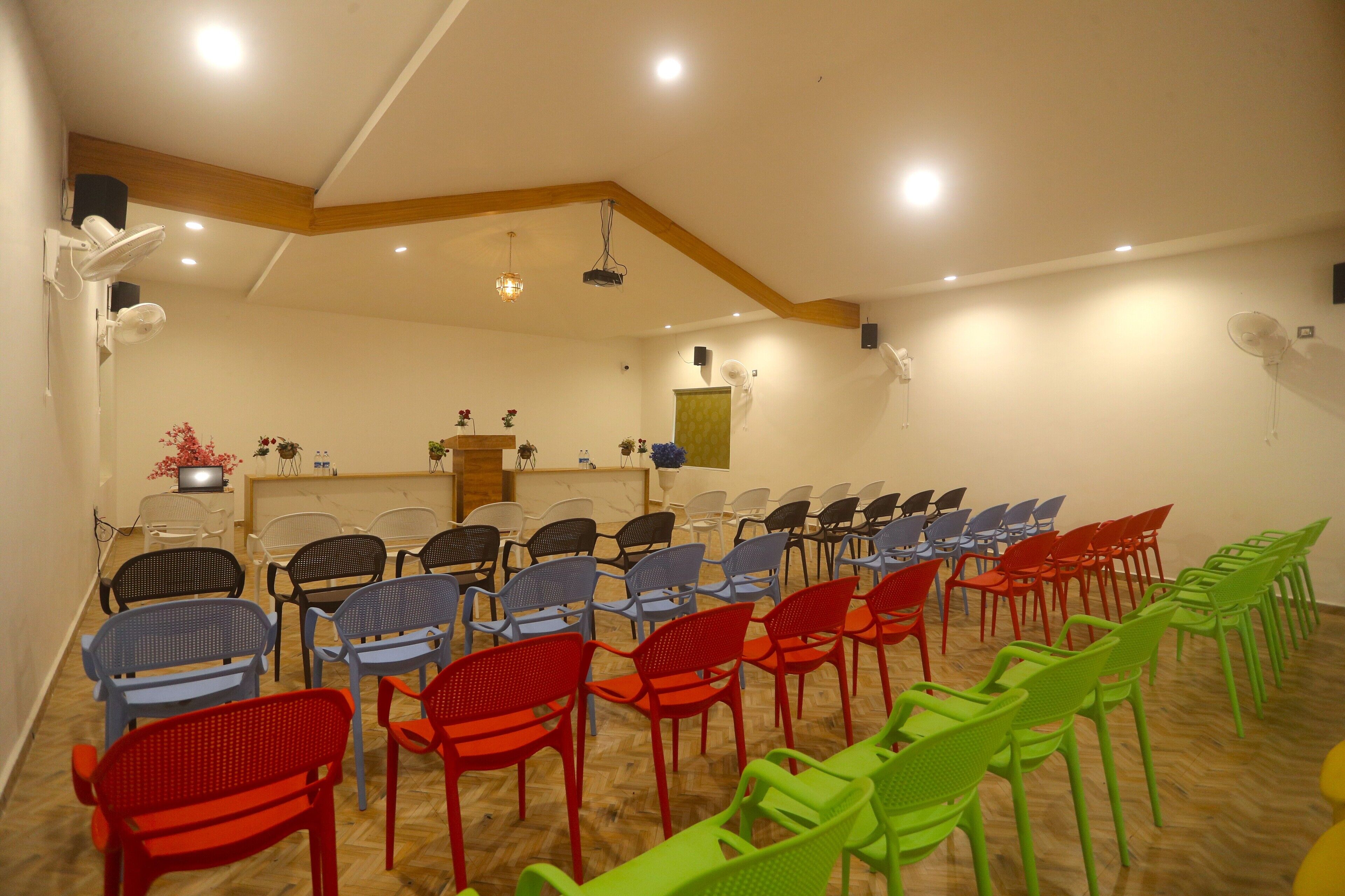 A conference room with rows of chairs, a podium, and ceiling lights.