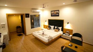 A hotel room with a bed, bedside tables, a desk, a chair, and a painting on the wall. - The Comfort Gir Resort (Mendarda)