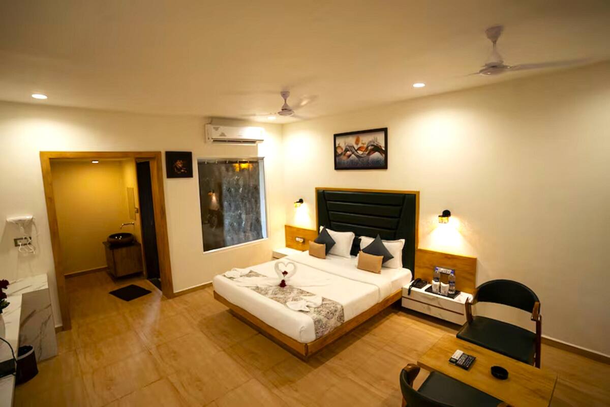 Habitación de hotel con cama, mesitas de noche, escritorio, una silla y un cuadro en la pared.