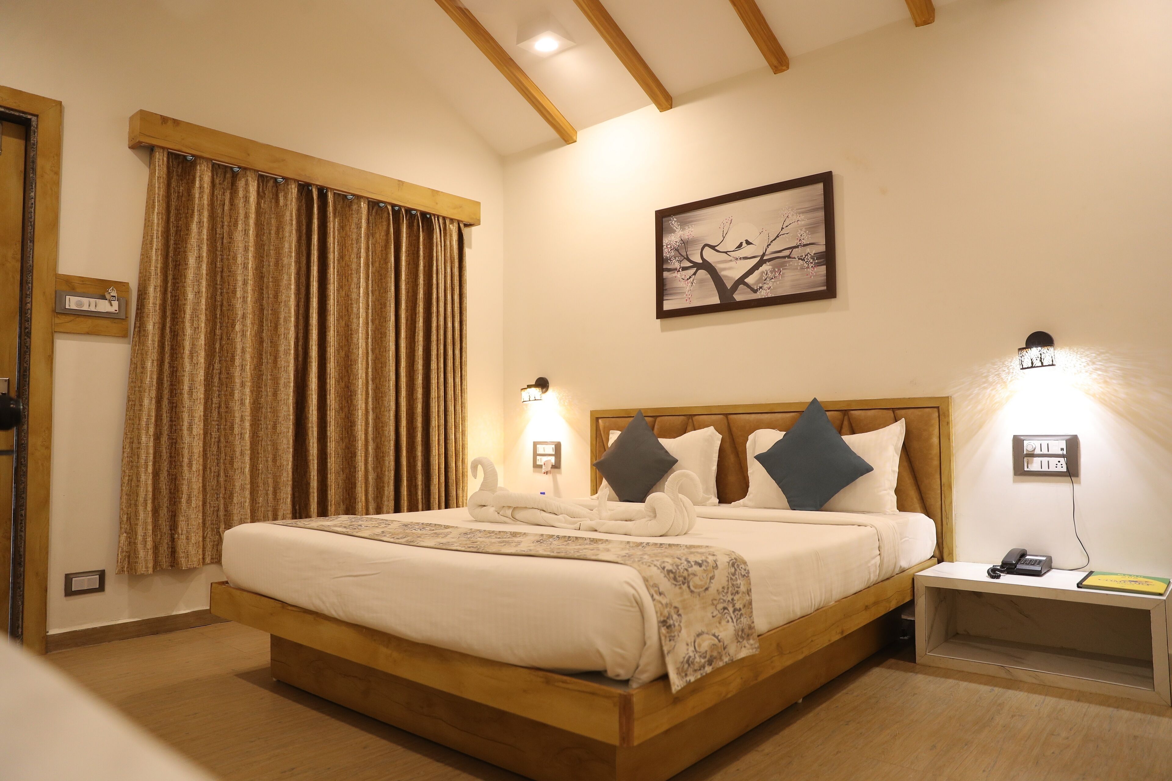 A neatly made bed with a wooden headboard, a bedside table with a lamp, and a wall-mounted painting.
