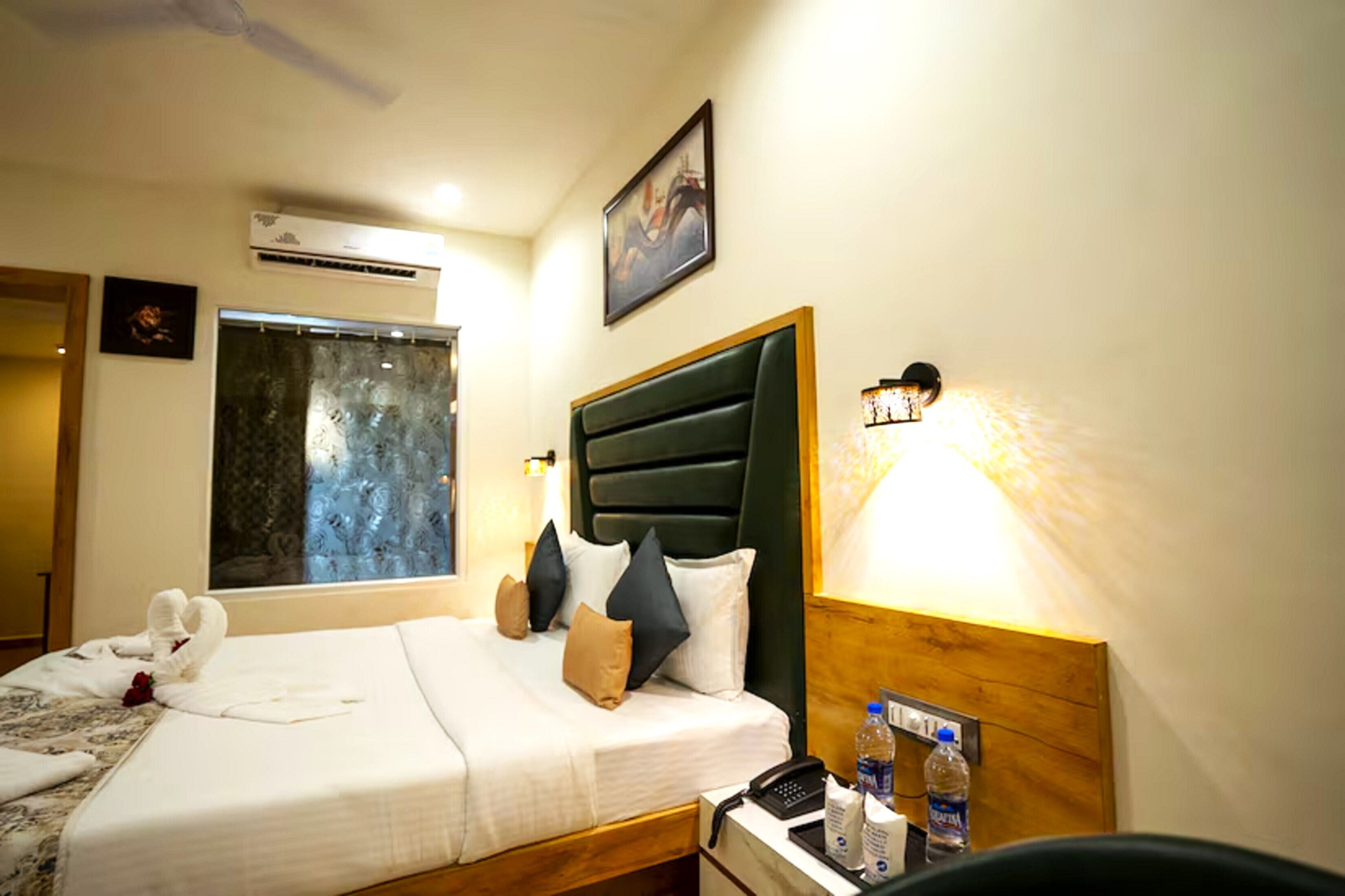 Une chambre d’hôtel avec un lit, une table de chevet avec une lampe, un téléphone et une bouteille d’eau.