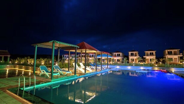 A nighttime swimming pool area with lounge chairs and a covered seating area. - The Comfort Gir Resort (Mendarda)