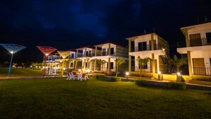 A hotel with multiple buildings, outdoor seating areas, and well-lit pathways. - The Comfort Gir Resort (Mendarda)
