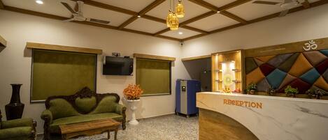 A reception area with a reception desk, a sofa, a coffee table, and a television on the wall.