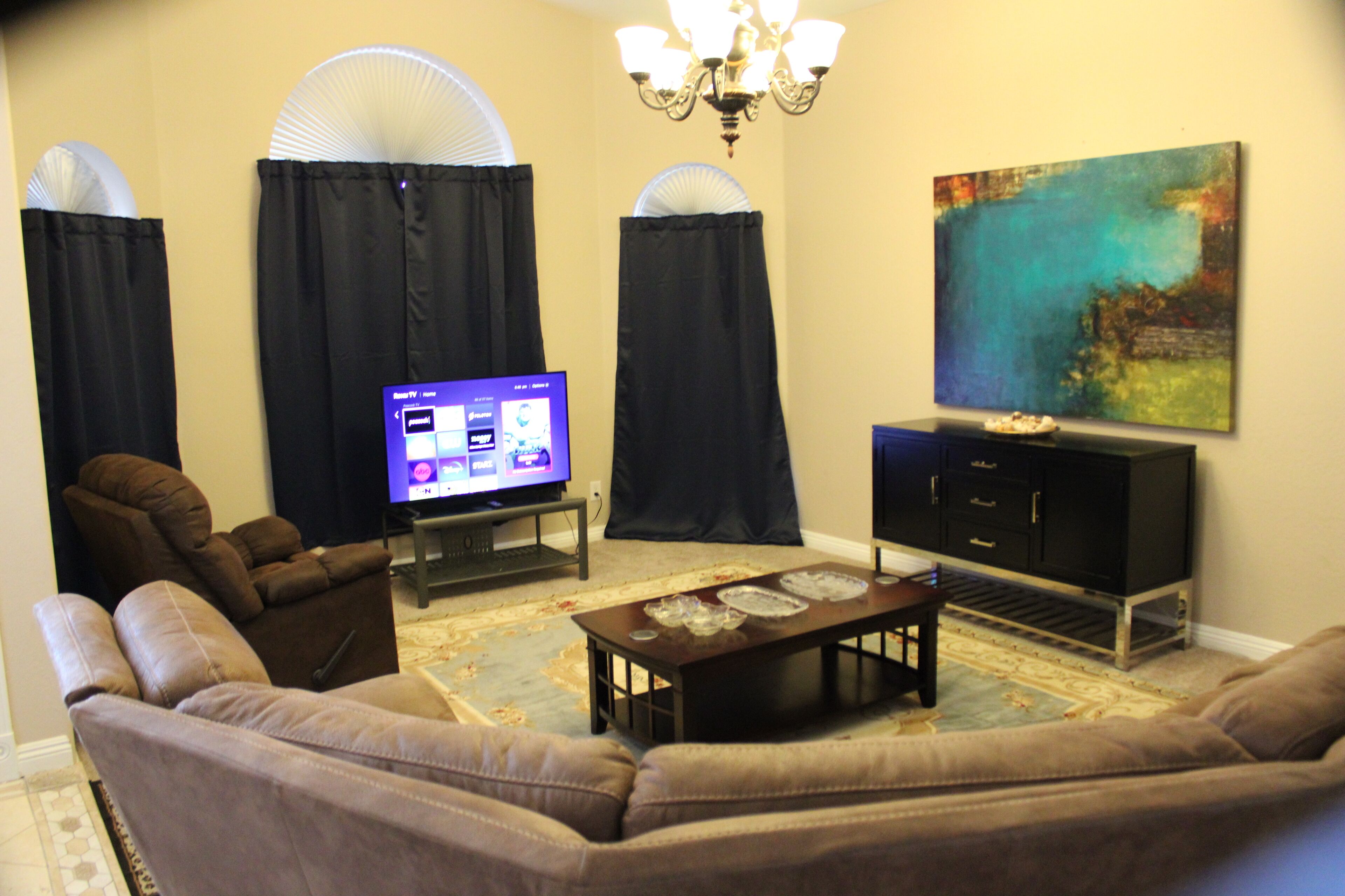 Una sala de estar con sofá, televisor, mueble y un cuadro en la pared.