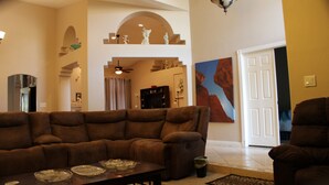 A living room with a brown sofa, a coffee table with glassware, and a painting on the wall. - New Fresh Water Single Level home 2.3 miles to Mayo Clinic, Kierland, WestWorld (Scottsdale)