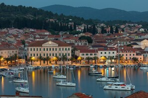 Un port de plaisance où sont amarrés de nombreux bateaux, entouré de bâtiments aux toits recouverts de tuiles rouges, et un bâtiment imposant doté d’un clocher.
