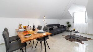 Una sala de estar moderna con comedor, que incluye una mesa de madera dispuesta para una comida, un sofá gris y un sofá de cuero.