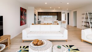 Ein modernes Wohnzimmer mit einem weißen Sofa, einem Couchtisch mit Dekoration und einem farbenfrohen Teppich.