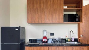A kitchen with wooden cabinets, a black refrigerator, a red blender, and a microwave. - Rooftop Pool Apt for 4 | Near Isla Ferry, Cancun (CancÃºn)