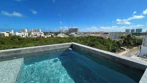 A rooftop infinity pool with a clear view of the city skyline. - Rooftop Pool Apt for 4 | Near Isla Ferry, Cancun (CancÃºn)