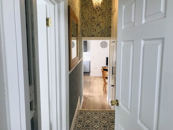 A hallway leading to a dining area with a patterned floor, a clock on the wall, and a wooden table. - Character Town Centre ,1 Bed Flat, Boston (Boston)