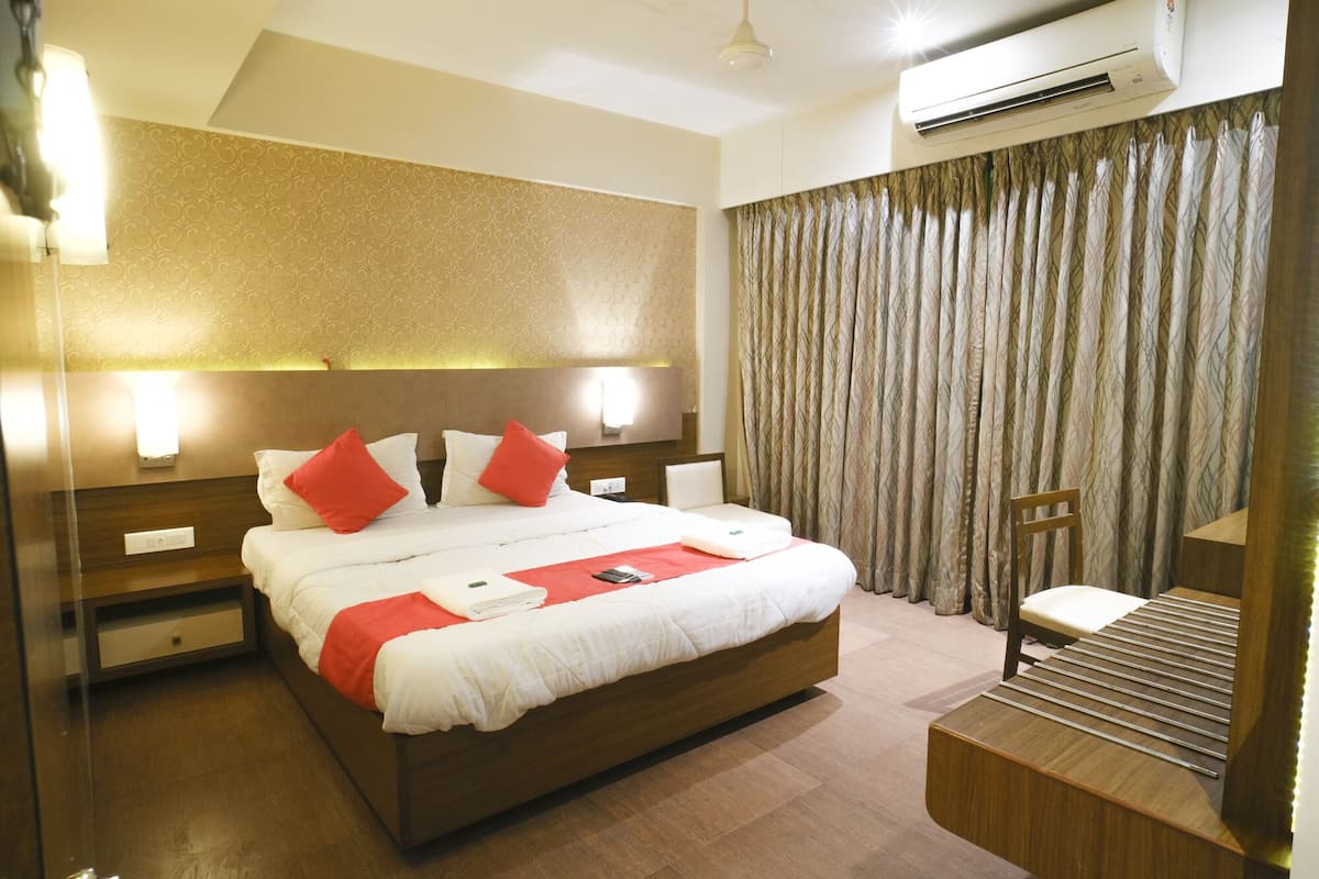 A hotel room with a large bed, bedside tables, a desk, and a chair.