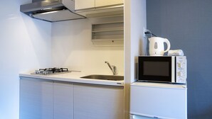 Een functionele keuken met een gasfornuis, een spoelbak, een magnetron en een inbouwoven.