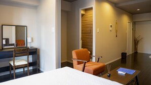 Hotelkamer met een bed, bureau met stoel, spiegel en deur naar een andere kamer.
