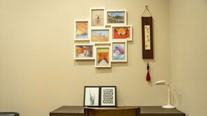 Een bureau met een stoel, een hanglamp en een muur met ingelijste foto’s.