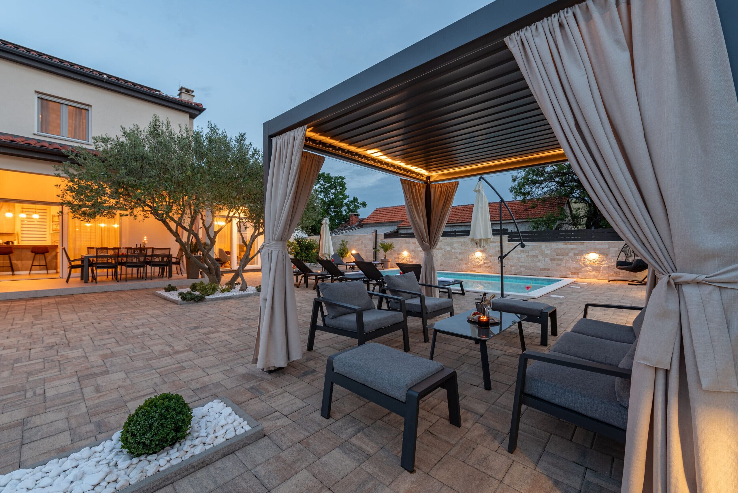 An outdoor patio area with seating, a pool, and a covered pergola.
