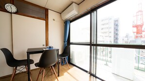 A room with a large window, a table with chairs, a clock, and an air conditioning unit. - Sakimoto Residence Namba Minami III (Osaka)