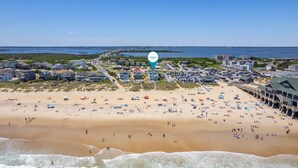 A coastal town with a beach, buildings, and a clear sky.