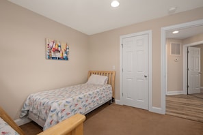 Een slaapkamer met een bed, een deur en een gang.