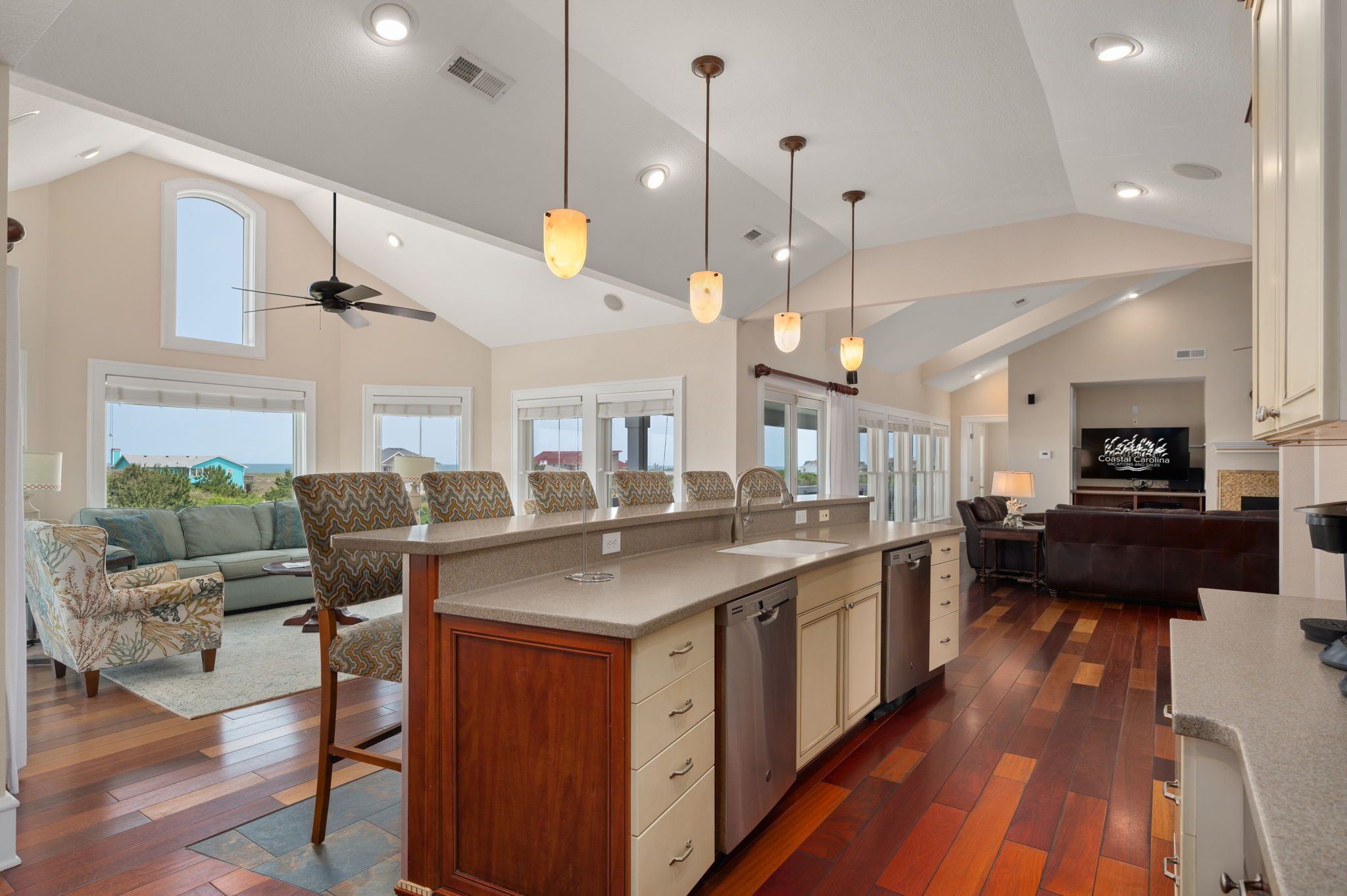 A spacious kitchen with a central island, overhead pendant lighting, and a view to the outside.
