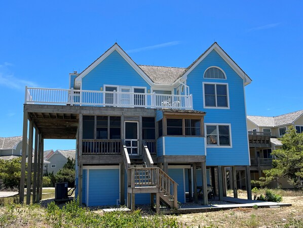 A two-story house with a balcony, wooden deck, and a garage.